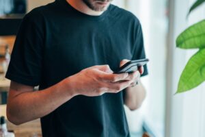 A man using his mobile phone to access nonprofit text platform benefits, showcasing why SMS is a game-changer for nonprofit fundraising